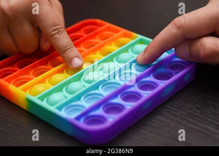 Children hands are competing for the speed of clicking on a color pop it. Stock Photo