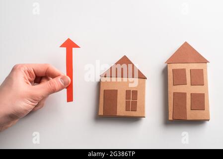 3d paper houses and hand holding a red arrow pointing up Stock Photo
