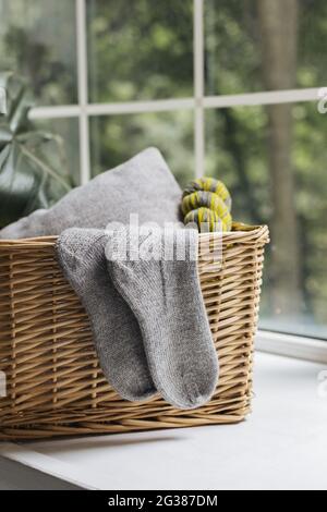 Pair of hand knitted socks on the basket in a sunlight. Grey socks. Stock Photo