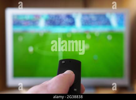 hand pointing remote control at tv set with soccer or football match Stock Photo