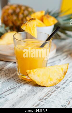 Fresh natural pineapple juice cocktail or fresh pineapple juice on white wooden table. Tasty juice in glass with ingredients pineapple slice. Stock Photo