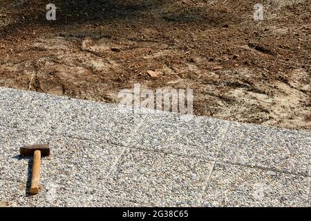 Garden brick path paving with hammer. Laying concrete paving slabs in the home garden on a foundation Stock Photo