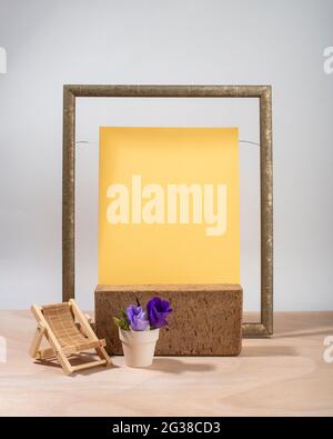 Composition of brick podium, wooden frame, wooden toy deck chair and flowers in a pot.  Summer concept. Template, mockup, podium for products and acce Stock Photo
