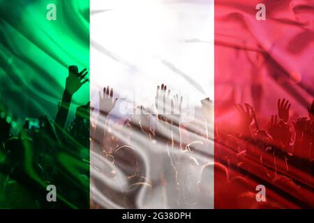 football fans supporting Italy - crowd celebrating in stadium with raised hands against Italy flag Stock Photo