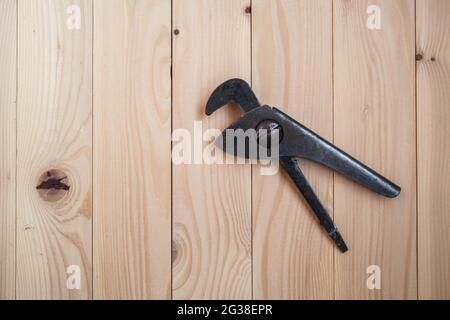 Old adjustable pipe wrench on a light wooden background. Plumbing wrench. Renovation concept. Stock Photo