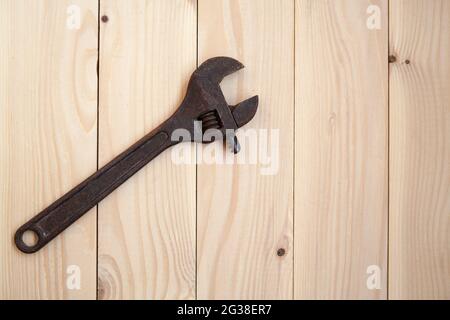 Old rusty adjustable wrench on a light wooden background. Work concept. Stock Photo