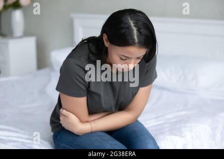 Frustrated unhappy girl feeling belly ache, strong stomach pain Stock Photo