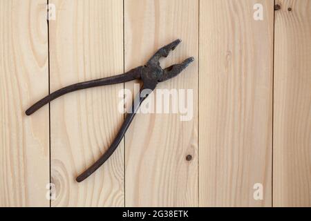 Old rusty pliers on a light wooden background. Pliers on the table, work concept. Stock Photo