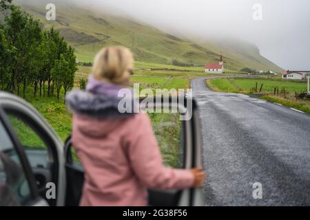 Woman enjoyed typical rural Icelandic Church with red roof from the rent car in Vik region. Iceland Stock Photo