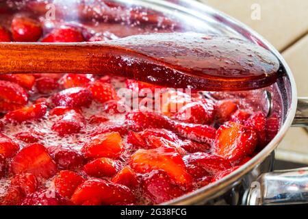 Making strawberry jam at home - wooden spoon on edge of stainless steel pot. Step 4 of 4. Stock Photo
