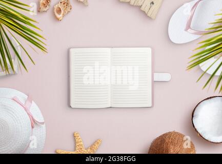 Notebook on beach surrounded by summer vacation accessories, shells and coconut. Empty notebook for text promotion Stock Photo