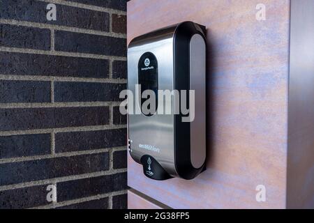 Kirkland, WA USA - circa May 2021: View of a black plastic hand sanitizer dispenser attached to a red brick wall on the outside of a building. Stock Photo