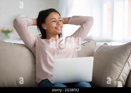 Happy relaxed female student, freelancer, customer relaxing on couch Stock Photo