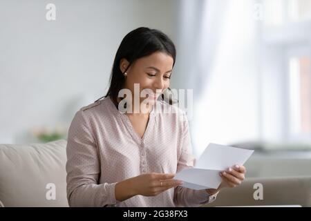 Happy young mixed race woman holding and reading paper letter Stock Photo