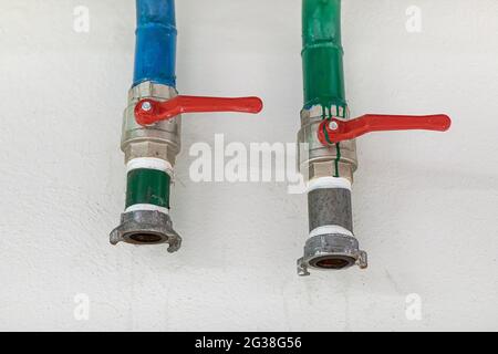 Two water tap with red valve handle inside building, at home. Fire safety equipment. Stock Photo