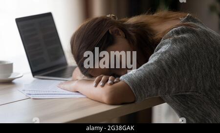 Close up exhausted unmotivated young woman sleeping at workplace Stock Photo