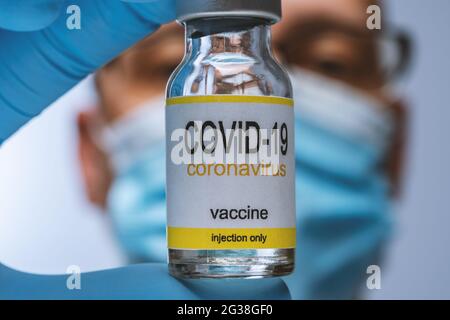 Doctor in blue latex gloves holding glass vial with medicine. Vaccination, immunization, treatment to Covid 19 Corona Virus infection. Healthcare And Stock Photo