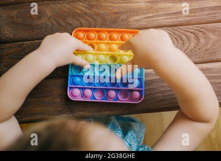Unrecognizable child bursts bubbles on a toy 'pop it'. Stock Photo