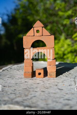 A tower made of small bricks outdoors on summer day. Construction concept. Children toys. Real estate concept Stock Photo