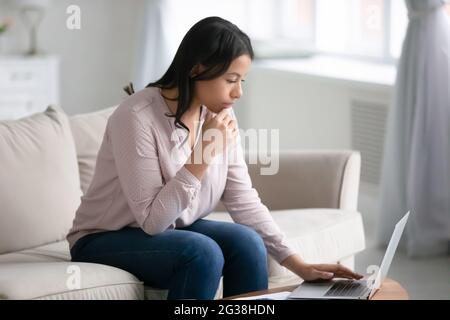 Thoughtful busy employee working from home, using laptop Stock Photo