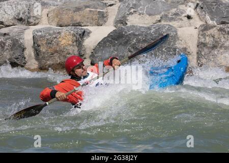 Man kayaking in freestyle competition through Class 2 rapids in Harvie Passage Whitewater Park on the Bow River, Calgary, Alberta, Canada Stock Photo
