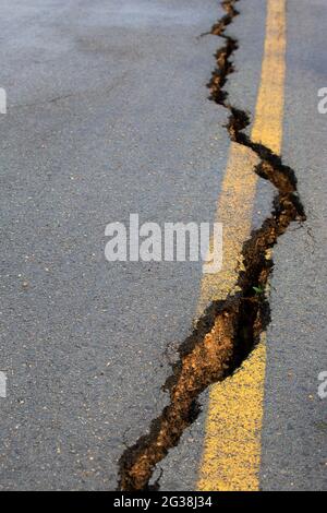 Crack in paved road with misaligned yellow line Stock Photo