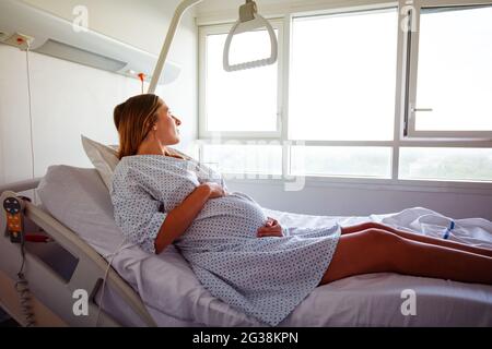 Pregnant woman laying in hospital bed hold belly Stock Photo