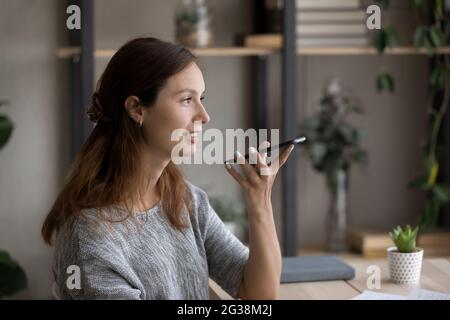 Side view smiling woman recording audio message on smartphone Stock Photo