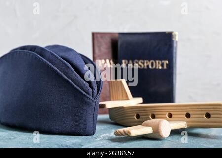 Stewardess hat with passport and plane figure on light background Stock Photo