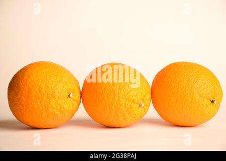 Three large identical oranges lie in a row on a white background Stock Photo