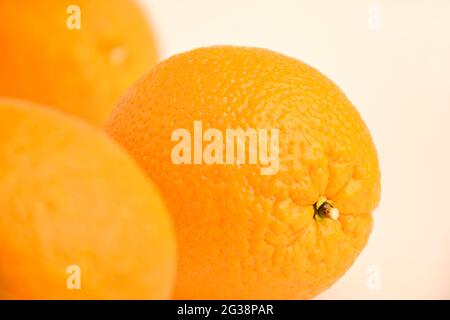 Three large oranges. One of them in sharpness, the other two on a blurred white background Stock Photo