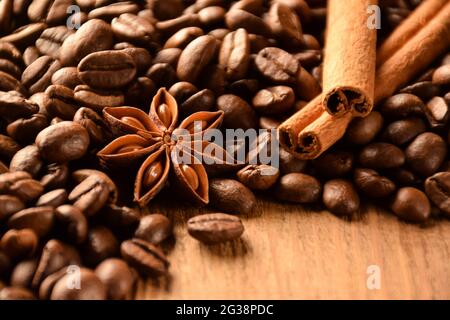 Many grains of coffee, anise and cinnamon lie on a brown wooden surface Stock Photo