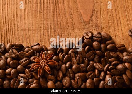 Sprinkled coffee beans at the bottom of the photo, as well as anise. Above photo of empty brown wooden background Stock Photo