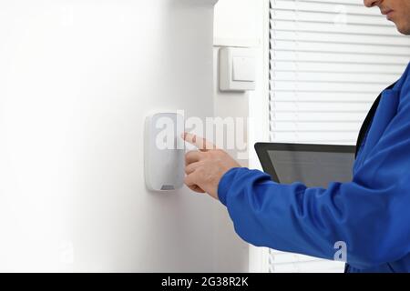 Worker with tablet computer checking alarm system indoors Stock Photo