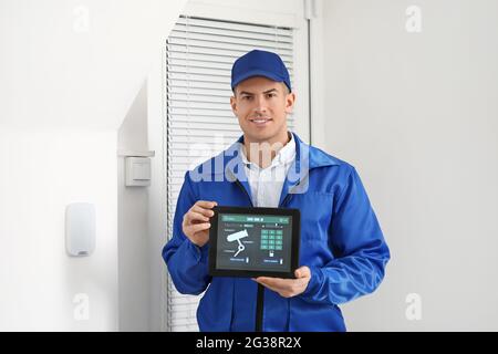 Worker with tablet computer checking alarm system indoors Stock Photo