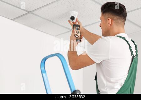 Worker with mobile phone checking alarm system indoors Stock Photo