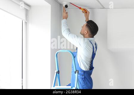 Worker installing CCTV camera in room Stock Photo