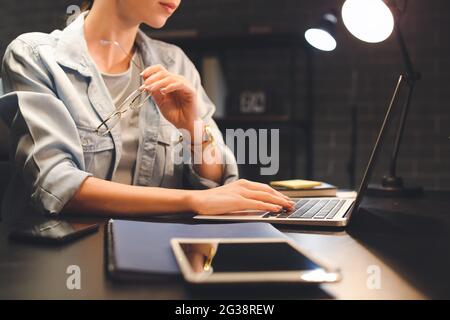 Young woman using laptop at home late in evening Stock Photo