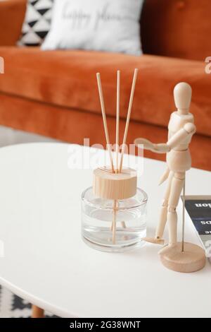 Reed diffuser and wooden mannequin on table in room Stock Photo