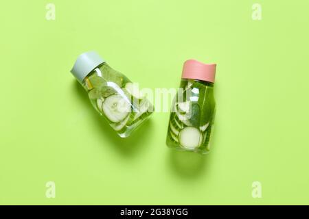 Bottles with cucumber lemonade on color background Stock Photo