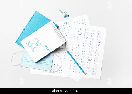 Stationery, answer sheet, mask and notebook with text ARE YOU READY? on white background Stock Photo