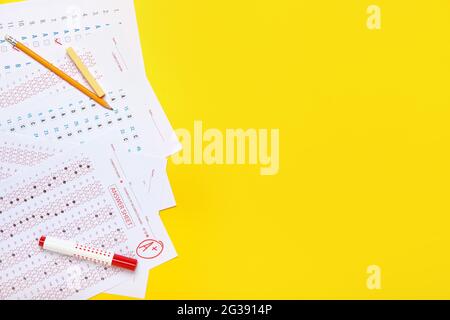 Checked answer sheets and stationery on color background Stock Photo