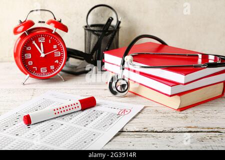Composition with answer sheet, stethoscope and alarm clock on wooden table Stock Photo