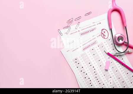 Checked answer sheets, stethoscope and stationery on color background Stock Photo