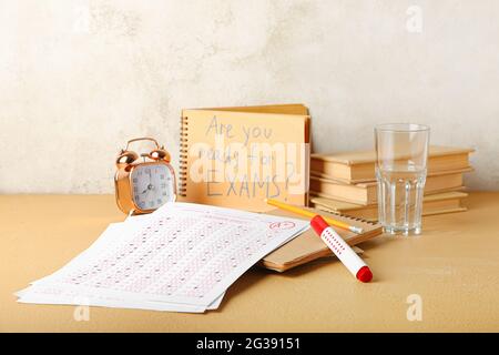 Answer sheets, stationery, alarm clock and notebook with text ARE YOU READY FOR EXAMS? on table Stock Photo
