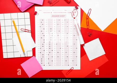 Checked answer sheet and stationery on color background Stock Photo