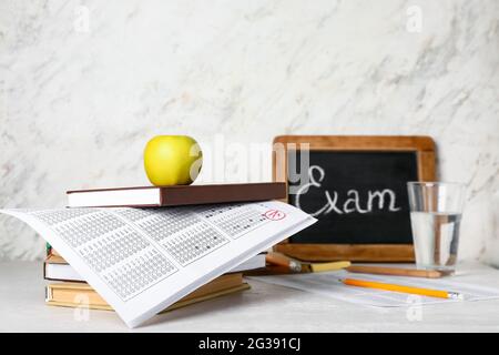 Stack of books and checked answer sheet forms on light background Stock Photo