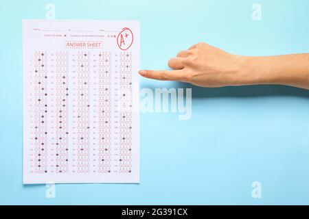Female hand with answer sheet form on color background Stock Photo