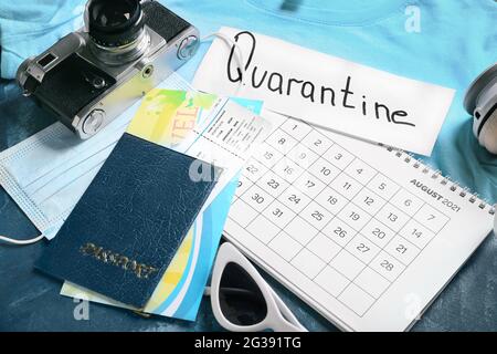 Calendar, travel accessories, medical mask and sheet of paper with text QUARANTINE on color background, closeup Stock Photo
