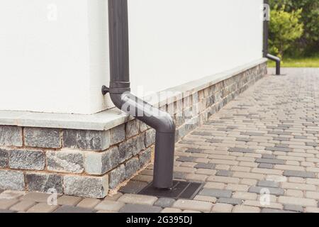 stormwater pipe on facade with rainwater drainage into drainage system with sewer manhole grill Stock Photo